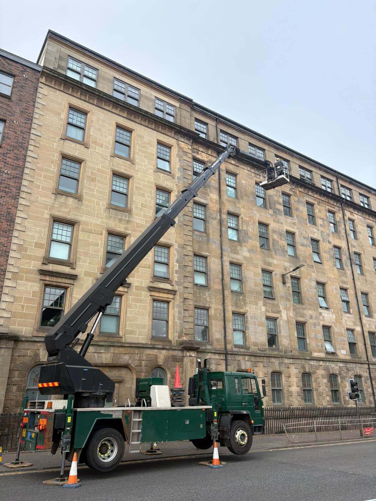 IPAF operator setting up truck-mounted cherry picker with safety cones in Glasgow